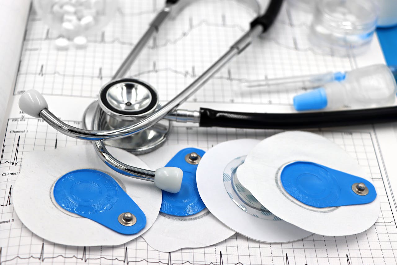 about-us-01 Close-up of medical tools including electrodes and stethoscope on ECG printout.